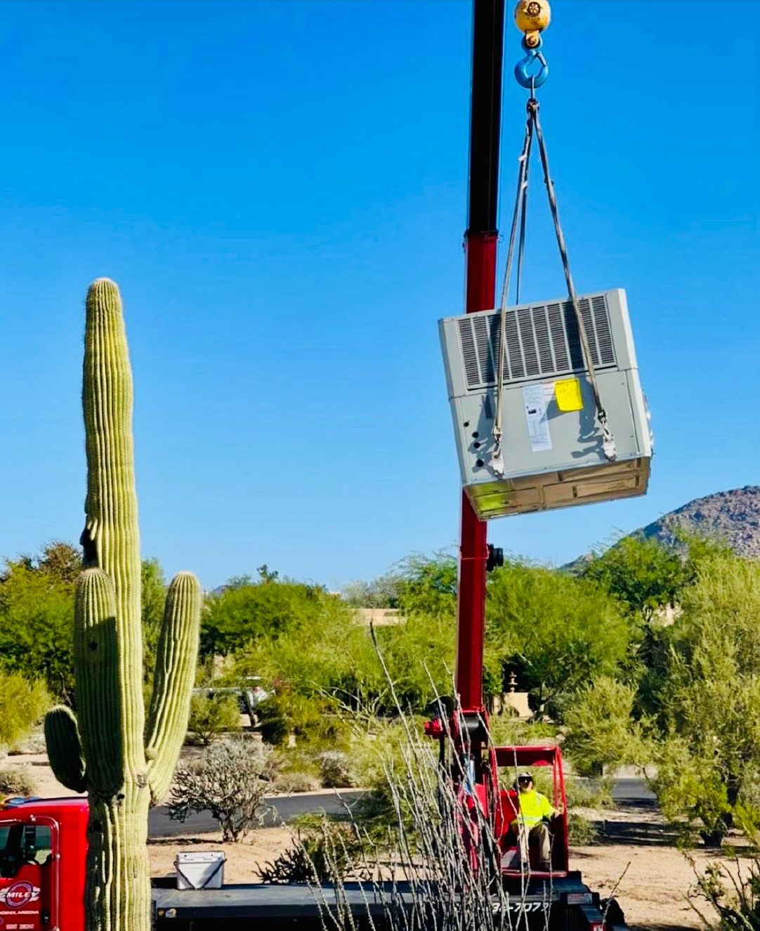 A new rooftop package unit lifted by crane beside a saguaro