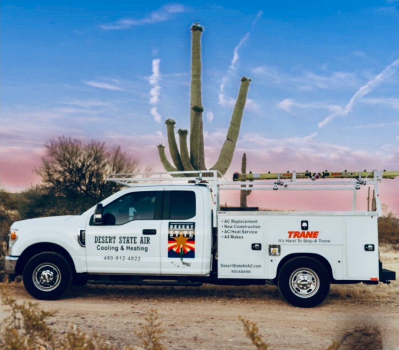 Desert State Air service truck with the company logo on the door, parked beneath a saguaro at sunset